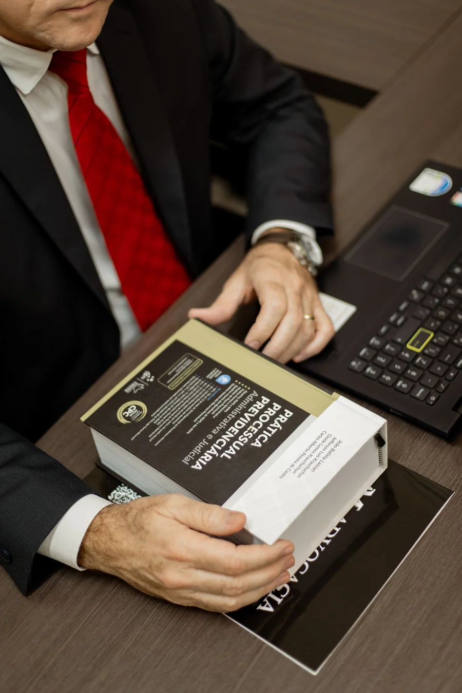 Detalhe de mesa com documentos jurídicos, caneta, óculos e celular durante análise contratual